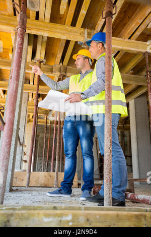 Supervisor of the construction site with architect looking building up on construction site Stock Photo