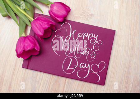 Three purple tulips with card and text Happy mothers day. Calligraphy lettering hand draw Stock Photo