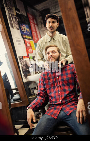 Male barber checking symmetry beard on client Stock Photo