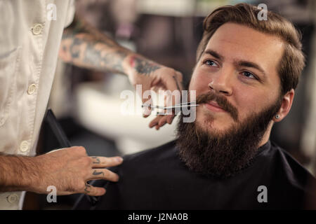 man barber with scissors cut the mustache smiling client Stock Photo