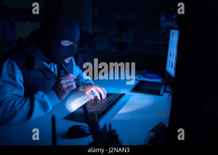 Computer hacker - Male thief stealing data from computer Stock Photo
