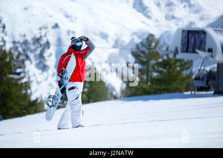 snowboarder relaxing and posing at sunny day on winter season with blue sky in background Stock Photo