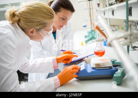Female technicians adjusting measuring instrument in laboratory Stock Photo