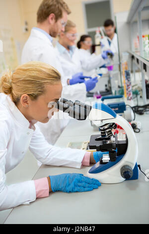 Young female chemical works with microscope in laboratory Stock Photo