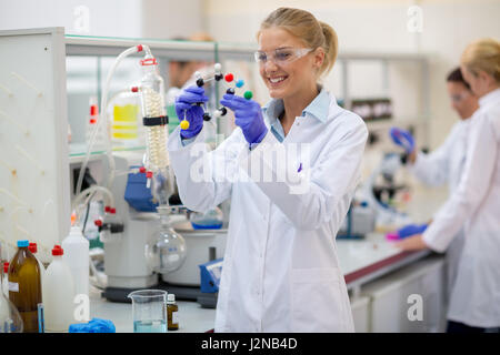 Young cheerful female chemist hold molecular model in lab Stock Photo