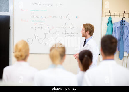 Young male chemical teacher teaching students in the classroom Stock Photo