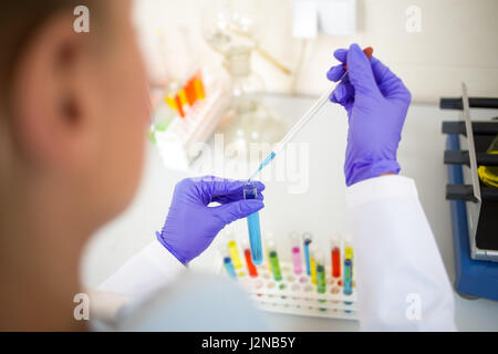 Close up view of lab technician sampling colorful liquids with glass pipette Stock Photo