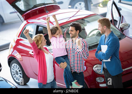 Happy and excited family celebrating just bought a new car from dealership Stock Photo