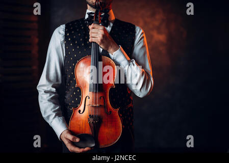 Portrait of male person holding wooden violin. Fiddler with musical instrument Stock Photo