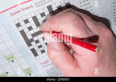 Man hand writing newspaper crossword UK Stock Photo