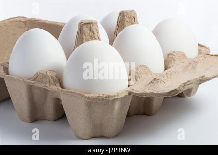 Six white eggs in recycled brown paper container on white background Stock Photo