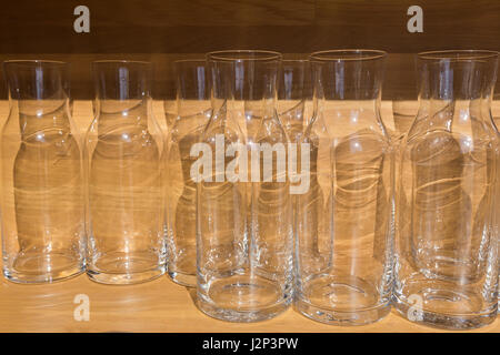clear empty glass bottles or jugs on wood table placing agaist wood wall in morning light, selective focus Stock Photo