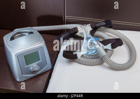 CPAP machine with air hose and head gear mask in a bedroom Stock Photo