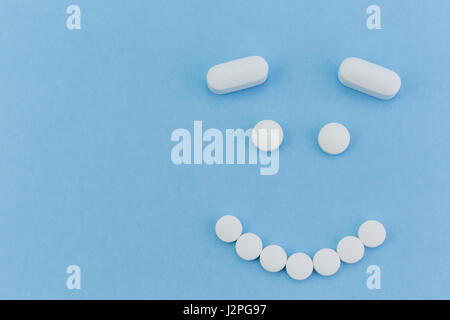 upset face made by pills on blue background Stock Photo
