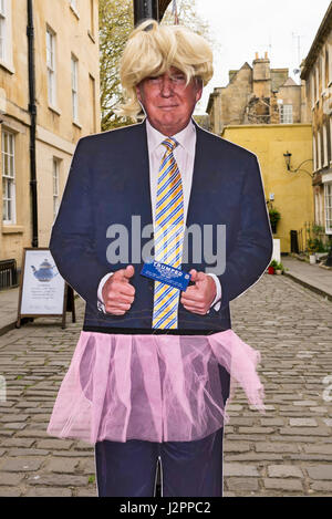 Real size copy of Donald Trump, current US president, in cardboard dressed up with a pink skirt and a blonde wig attached to a street lamp in a street Stock Photo