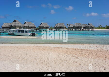 Tropical overwater bungalows in the lagoon seen from a sandy beach shore, atoll of Tikehau, Tuamotu, French Polynesia, south Pacific ocean Stock Photo