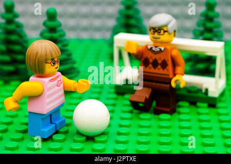 Tambov, Russian Federation - September 21, 2016 Lego girl playing football with her grandfather in park. Focus on girl. Studio shot. Stock Photo