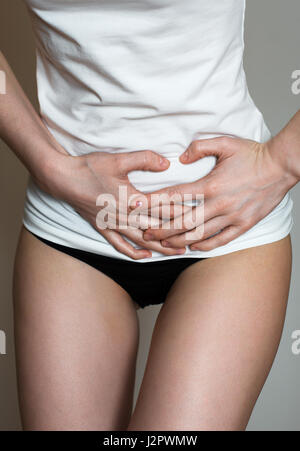 Unrecognizable woman on the bed with stomach pain. Stock Photo