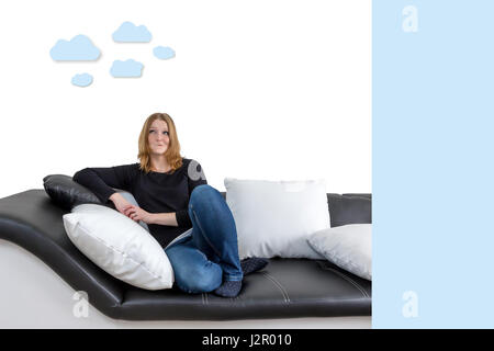 Grinning long haired young woman is sitting on a black and white couch with black and white pillows. Woman is looking upwards on the illustration of c Stock Photo