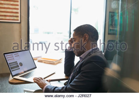 Focused African American businessman working at laptop in office