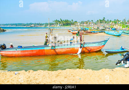 HIKKADUWA, SRI LANKA - DECEMBER 4, 2016: The hard physical work of Sri Lankan fishermen, every day they need to pull their boat to the shore and then  Stock Photo