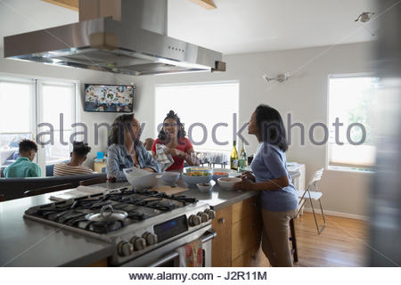 African American mother and teenage daughters cooking and eating in kitchen