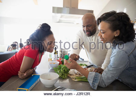 African American family cooking, looking at bottle in kitchen