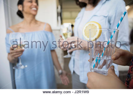 Women drinking white wine and lemon water on patio