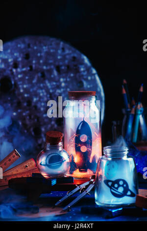 Space themed still life with rocket, planets and asteroid inside jars on a dark background Stock Photo