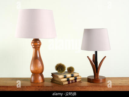 Decorative wooden table lamps with white shades close-up on shelf with books, against light background Stock Photo