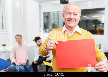 Senior man holds blank sign at creative idea brainstorming workshop Stock Photo