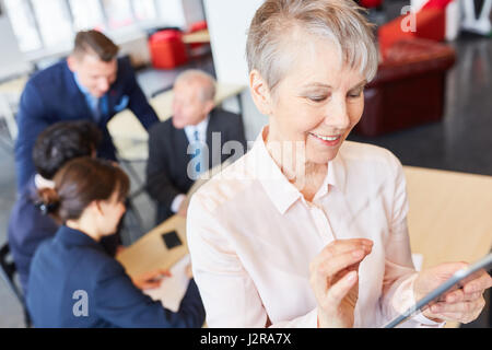 Senior woman using tablet computer in business training workshop Stock Photo