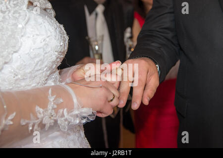 Newlyweds. Bride puts a wedding ring on groom. Hands of newlyweds and wedding rings. Commitment, happiness and love Stock Photo