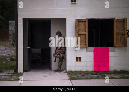 Members of the New Jersey Army National Guard portray enemy forces (also known as OpFor) during a movement to contact exercise at Fort Dix, New Jersey on 26 April 2017 during the Region One Best Warrior Competition. Soldiers taking part in the exercise moved from building to building, clearing rooms and retrieving the rescue dummy before being retrieved by friendly forces.    Fourteen Soldiers are competing in the three-day event, April 25-27, 2017, which features timed events, including urban warfare simulations, a 12-mile ruck march, land navigation, and the Army Physical Fitness Test. The t Stock Photo