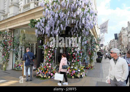 Artificial flowers with wisteria greet shoppers at the entrance of Fenwick's department store at  Brook St and New Bond Street London UK  KATHY DEWITT Stock Photo