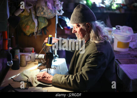 A senior adult man sewing a piece of cloth on a sewing machine. Stock Photo