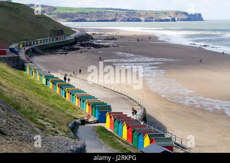 Row of brightly coloured wooden beach huts along the West Cliff promenade at Whitby, North Yorkshire, England, UK Stock Photo