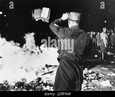 A member of the SA throws confiscated books into the bonfire during the public burning of 'un-German' books on the Opernplatz in Berlin. Stock Photo