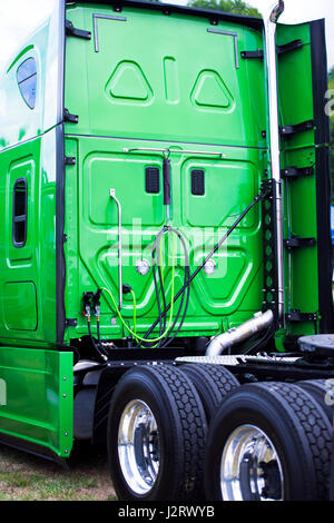 A big green modern rig semi truck with a high cabin with flat rear wall, a fifth wheel and two axle with new tires on lightweight aluminum rims. Stock Photo