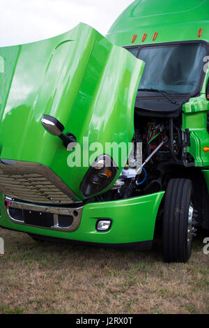 Huge professional bright shiny clean green big rig semi truck with an open hood to check the performance of the diesel engine of this royal transport  Stock Photo