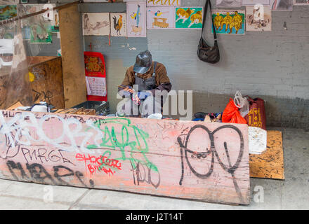 Old Asian man repairing shoes on a city street in Chinatown in New York City Stock Photo