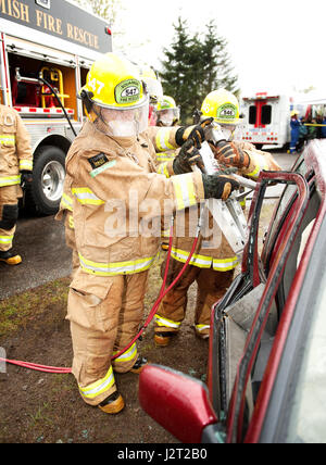 Trainee fire fighters and Howe Sound Secondary students Mary Cooke and Kei Gray use the Jaws of Life during a vehicle extraction exercise. Stock Photo