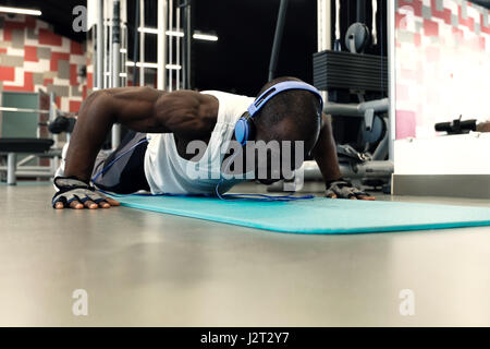 Sport. Young athletic man doing push-ups at gym. Muscular and strong black guy exercising. Stock Photo