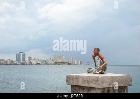 HAVANA - JUNE, 2011: Young Cuban sits on the seafront wall of the Malecon, the popular local gathering place. Stock Photo