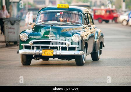 HAVANA - JUNE, 2011: Vintage American car serving as taxi drives along a street in a typical scene in Centro. Stock Photo