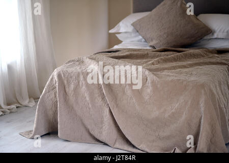 Luxury bedspread on unmade bed. Stock Photo