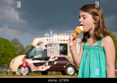 Horizontal portrait of a child eating ice cream in the sun. Stock Photo