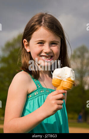 Vertical portrait of a young girl eating an ice-cream in the sun. Stock Photo