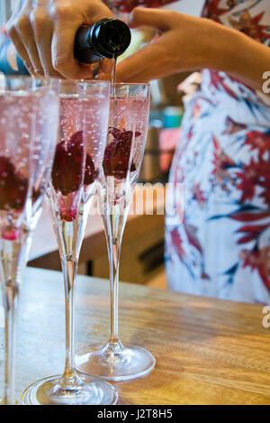 Vertical close up view of champagne flutes being filled up with alcohol. Stock Photo