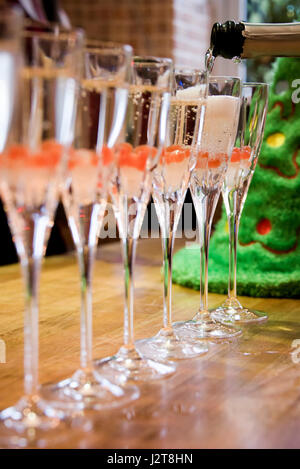 Vertical close up view of champagne flutes being filled up with alcohol. Stock Photo